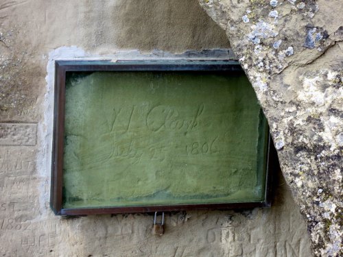 A weathered plaque embedded in a rock, inscribed with "W. J. Clark, July 25, 1806," partially obscured by stone.