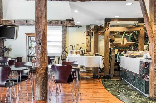 A cozy dining area with wooden beams, round tables, and a buffet setup featuring various food items.