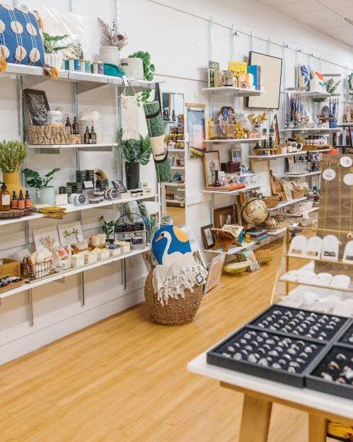 A bright store interior with shelves displaying various home goods, decor, and accessories, plus a decorative swan basket.
