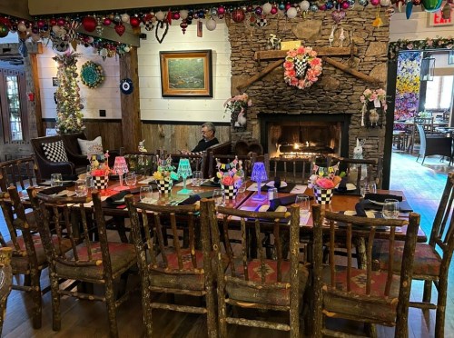 Cozy dining room with a large wooden table, colorful lamps, a fireplace, and festive decorations.