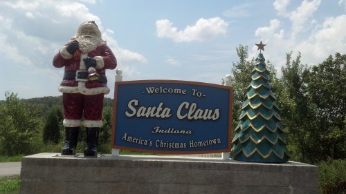 Welcome sign for Santa Claus, Indiana, featuring a Santa statue and a decorated Christmas tree.