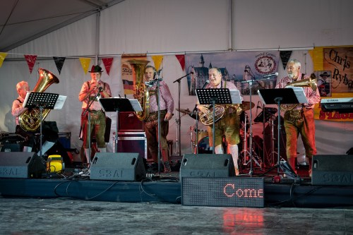 A lively band in traditional attire performs on stage, surrounded by instruments and festive decorations.