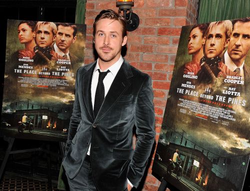 Ryan Gosling poses in front of promotional posters for "The Place Beyond the Pines" at a film event.