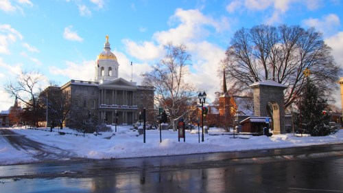 Snow-covered landscape featuring a historic building with a golden dome, under a bright blue sky with scattered clouds.