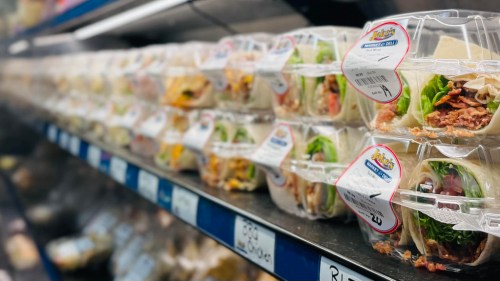 A display of neatly arranged pre-packaged sandwiches in clear containers on a supermarket shelf.