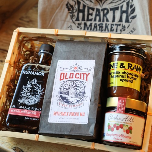 A gift basket featuring maple syrup, pancake mix, hazelnut butter spread, and raspberry hibiscus preserves.