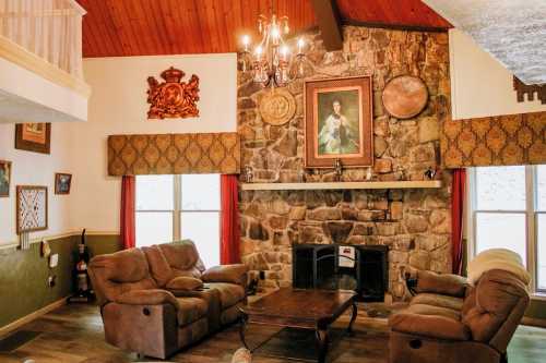 Cozy living room with stone fireplace, two armchairs, a wooden coffee table, and decorative wall art.