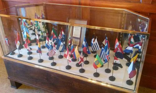 A display case containing various national flags on stands, arranged neatly in a row.