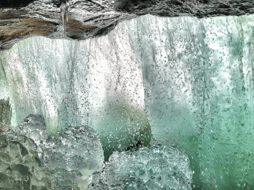 A close-up view of cascading water with bubbles and splashes, creating a serene, textured surface.