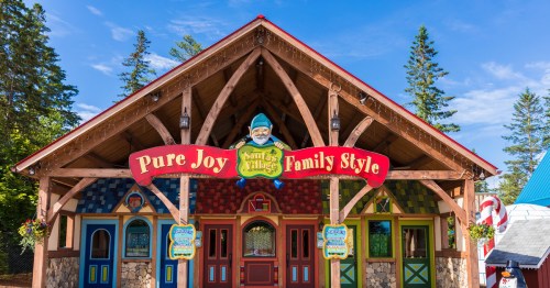 Colorful entrance to a whimsical building with "Pure Joy Family Style" sign, surrounded by trees and blue sky.