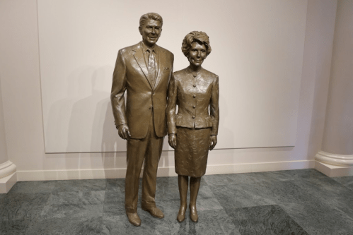 Bronze statue of Ronald and Nancy Reagan standing together, displayed in a gallery setting.