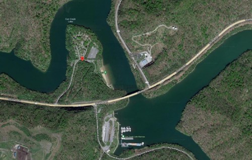 Aerial view of a lake area with roads, marinas, and green wooded surroundings.