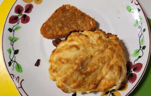 A plate with a golden biscuit and a triangular hash brown, surrounded by floral decorations.