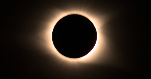 A solar eclipse with a dark circle surrounded by a glowing halo of light.