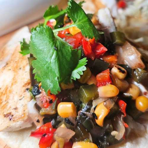 Close-up of a taco topped with grilled fish, fresh cilantro, corn, diced peppers, and onions.