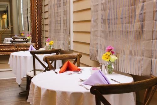 A cozy restaurant setting with two elegantly set tables, colorful flowers, and soft lighting.