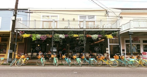 A colorful storefront with hanging flowers and parked bicycles in front, creating a vibrant street scene.