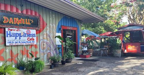 Colorful exterior of Darwell's Happiness Cafe with outdoor seating and plants in Long Beach, MS.