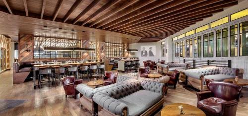 Stylish restaurant interior with wooden beams, cozy seating, and a bar area, featuring modern decor and warm lighting.