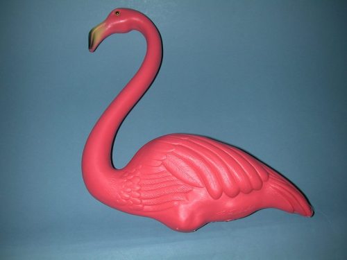 A pink plastic flamingo figurine with a long neck and detailed wings against a blue background.