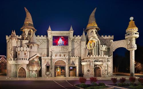 A whimsical castle-themed building with towers and turrets, illuminated at night against a dark sky.