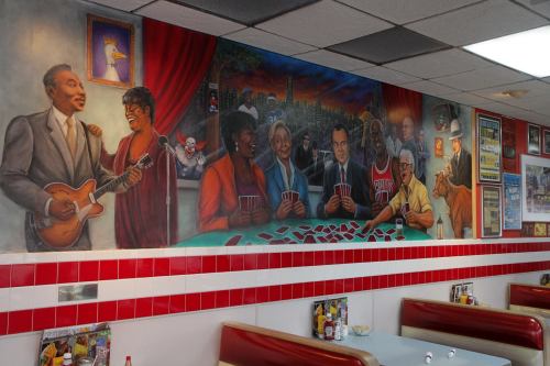 A colorful mural depicting musicians and card players in a diner setting, with vibrant characters and a lively atmosphere.
