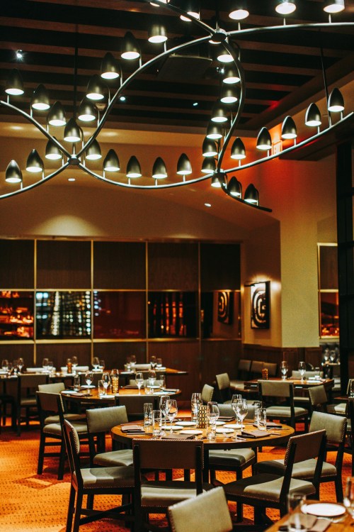 Elegant restaurant interior with modern lighting, neatly set tables, and a warm ambiance.