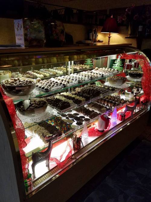 A display case filled with an assortment of chocolates and sweets, decorated with festive ribbons and lights.