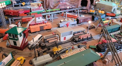 A colorful model train setup featuring various trains, buildings, and tracks in a detailed miniature landscape.