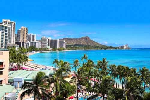 A vibrant beach scene in Waikiki, with clear blue water, palm trees, and Diamond Head in the background.