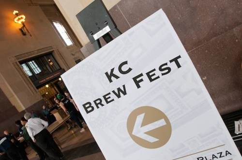 Sign for "KC Brew Fest" with an arrow pointing left, set in a bustling indoor venue.