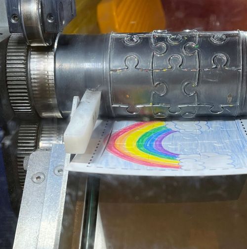 A close-up of a machine with a colorful rainbow drawing being processed through it.