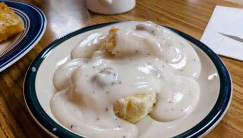 A plate of biscuits smothered in creamy sausage gravy, served on a wooden table.