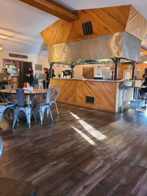 A cozy restaurant interior featuring a wooden counter, metal accents, and tables with chairs in a warm, inviting atmosphere.