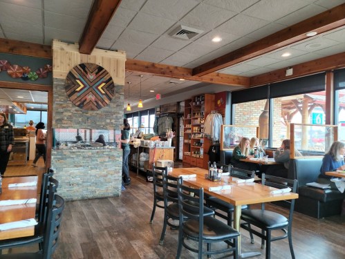 Interior of a cozy restaurant featuring wooden decor, stone accents, and diners at tables.