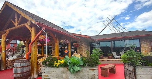 A charming restaurant exterior with wooden beams, colorful flower baskets, and a garden area in front.