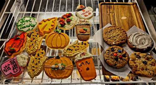 A variety of decorated cookies, including pumpkins, flowers, and seasonal designs, alongside chocolate chip cookies.