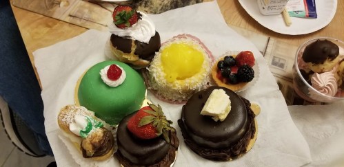 A variety of colorful pastries, including cream-filled and fruit-topped desserts, arranged on a white napkin.