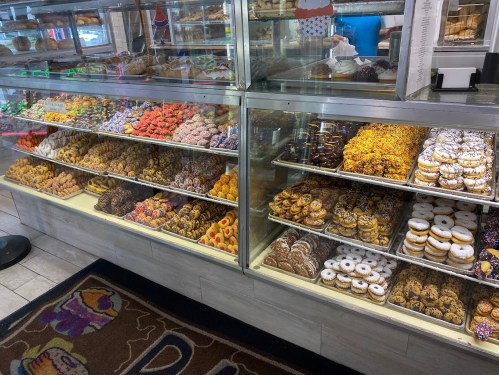 A display case filled with a variety of colorful donuts and pastries in a bakery.