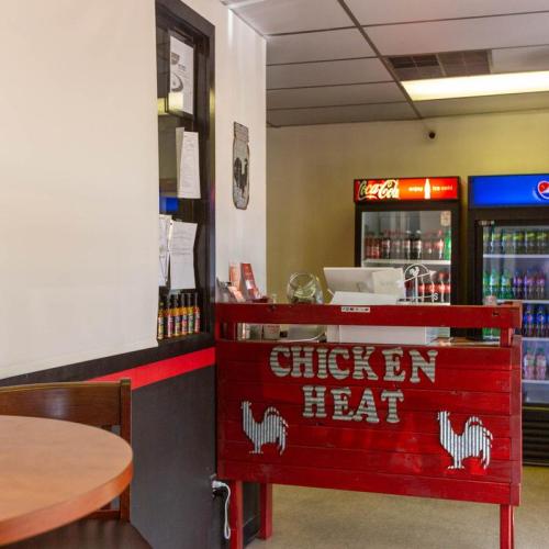 Interior of a casual eatery with a red "Chicken Heat" sign, tables, and a drink cooler in the background.