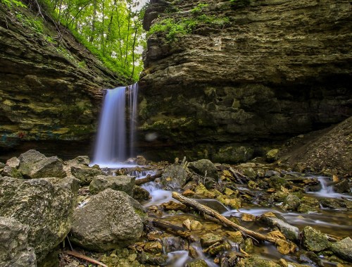 A serene waterfall cascades over rocks in a lush, green forest setting.