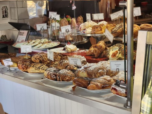A display of various pastries and baked goods, including croissants, danishes, and cookies, in a bakery.