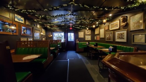 Cozy restaurant interior with green booths, framed art on the walls, and warm lighting from string lights.
