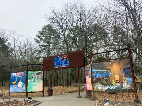 Entrance to Mid-America Science Museum, featuring colorful banners for various exhibits among bare trees.