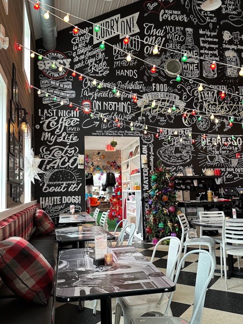 A cozy restaurant interior with a black chalkboard wall filled with colorful text and festive decorations.