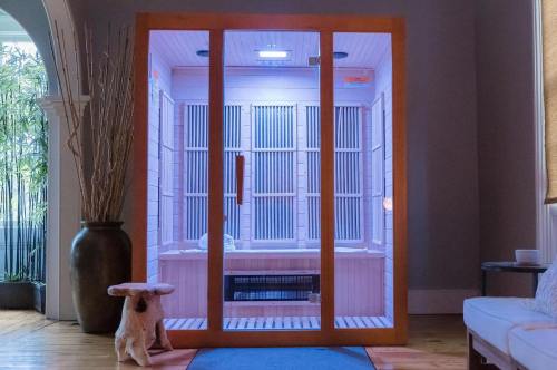 A modern infrared sauna with glass doors, set in a cozy room with a plant and a small table.