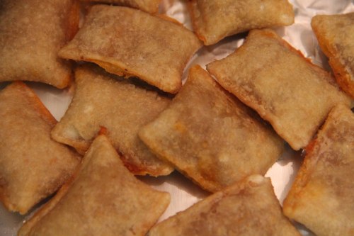 A close-up of golden-brown, crispy stuffed pastries arranged on a silver tray.