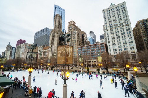 A bustling ice skating rink surrounded by tall city buildings, with people skating and enjoying the winter atmosphere.