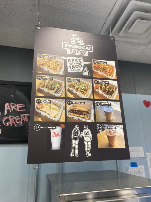 Menu board featuring various taco dishes and drinks, including tacos, burritos, and iced coffee options.