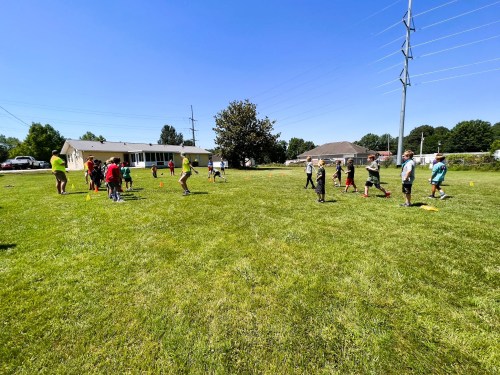 Children playing outside on a sunny day, engaging in activities on a grassy field near a house.